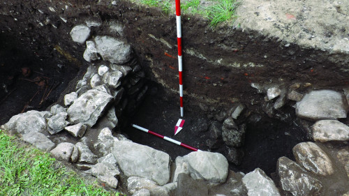 Fig. 5. Structură de piatră legată cu pământ (fântână?), parțial prăbușită, în capătul de vest al curții bisericii; în partea stângă, groapă cu oase istorică.